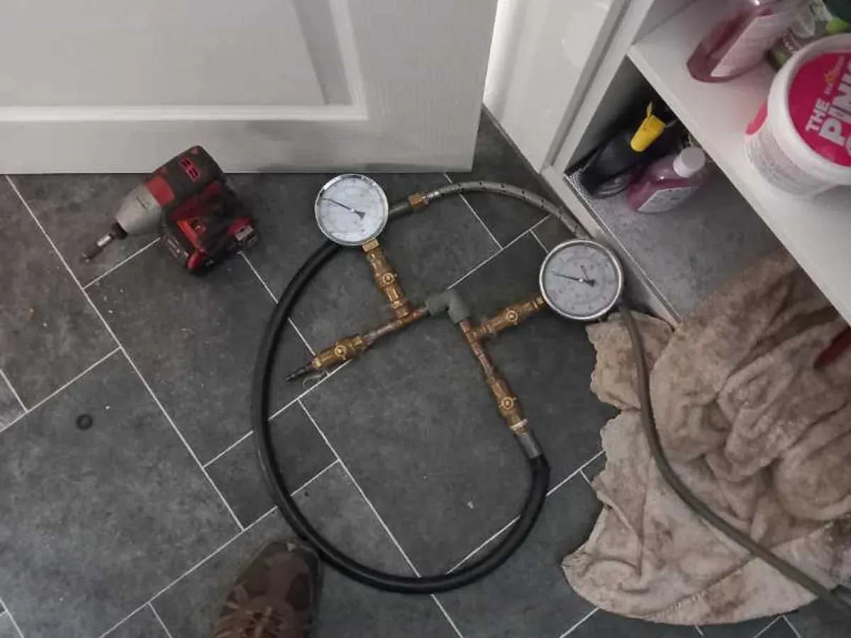 Two pressure gauges on a hose rig laid on the kitchen floor