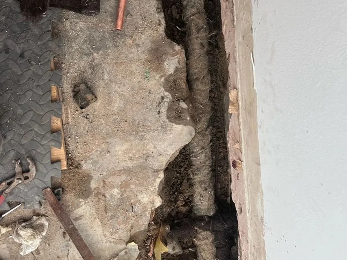 Trench in a concrete floor with bare copper pipes laid in it