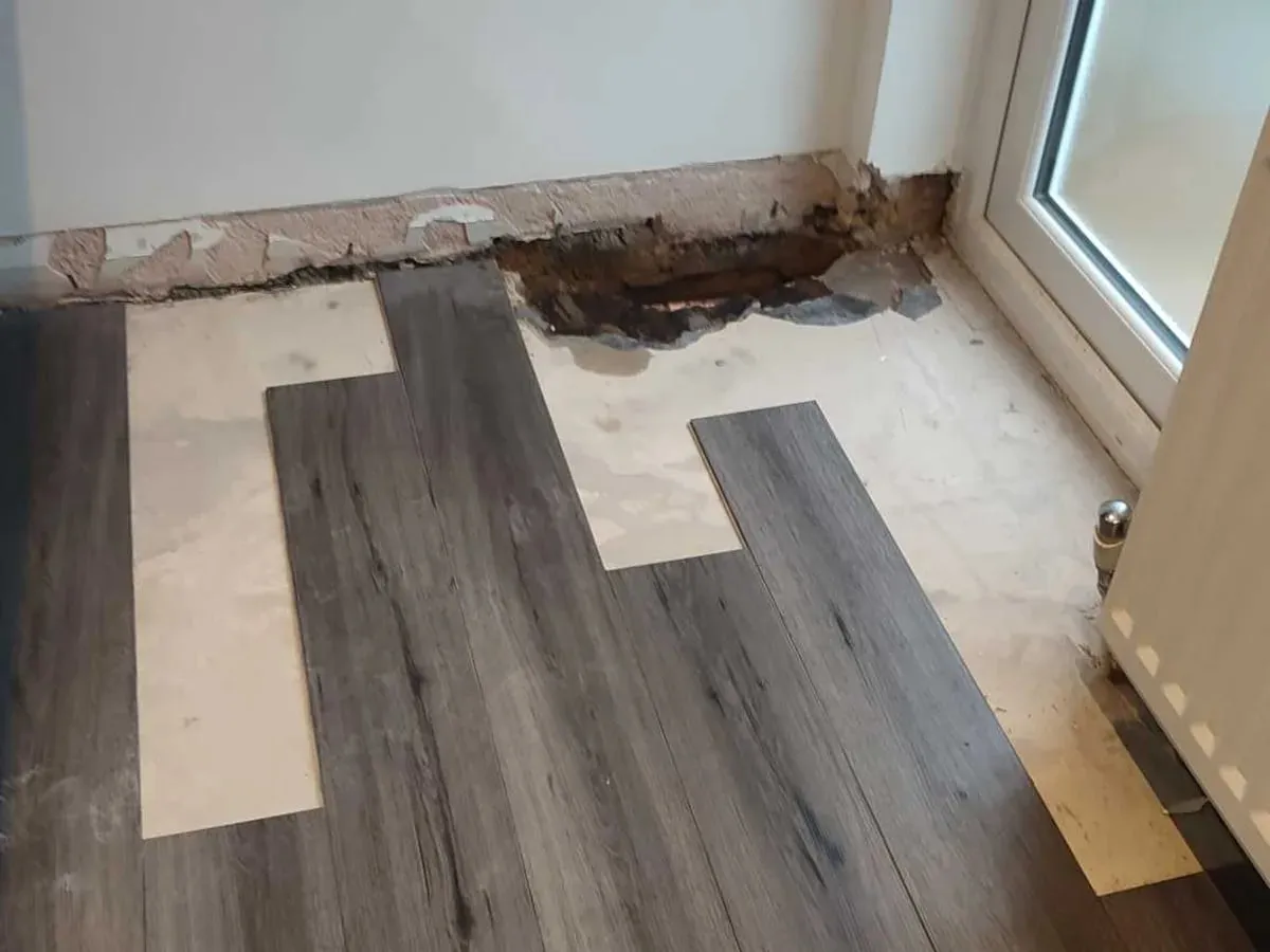 Laminate boards lifted in a small area by the wall with the screed patched