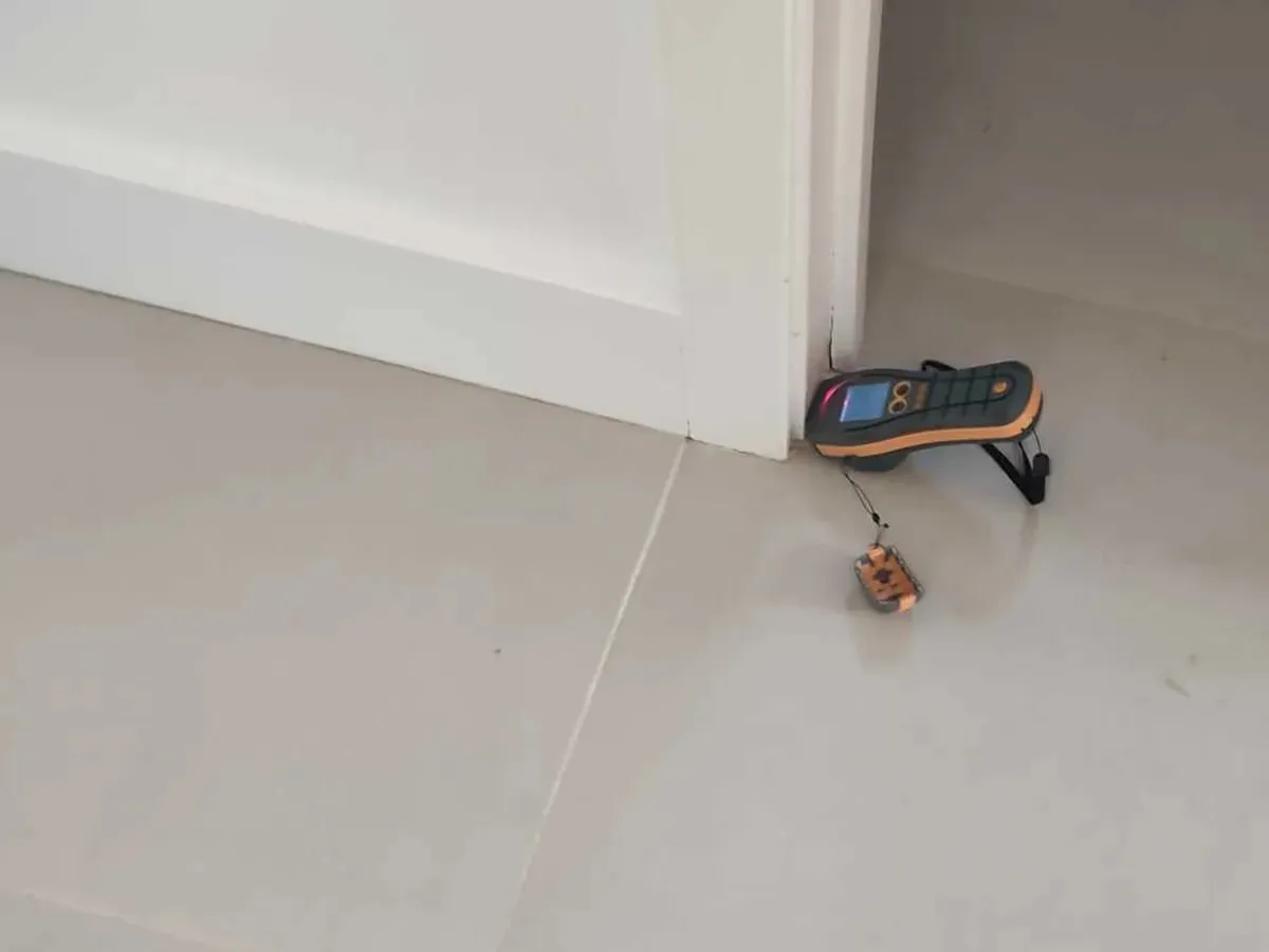 Moisture meter resting on the tiled floor at a doorway threshold