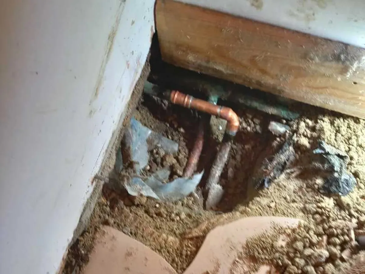 New copper pipe and elbow fitted in an opened hole by the wall