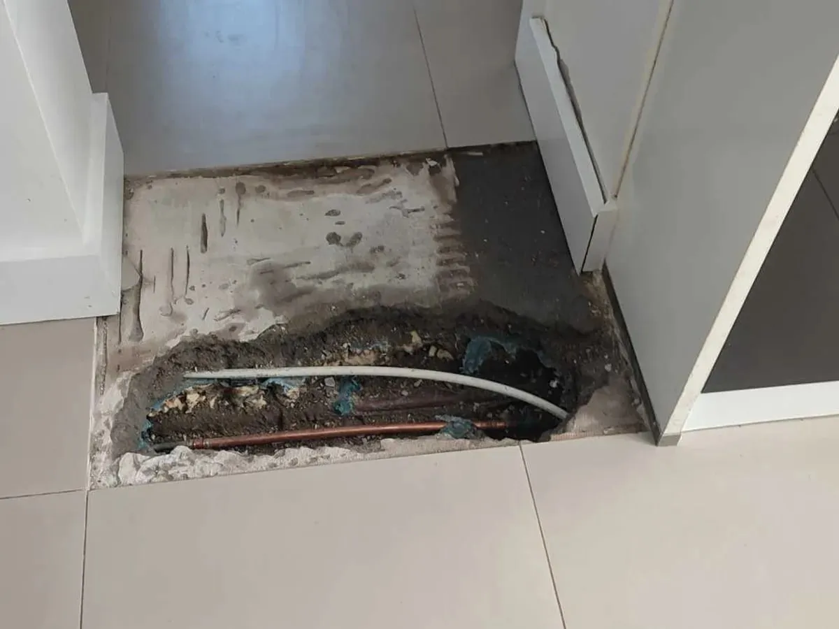 New copper pipe section laid in the opened strip of floor