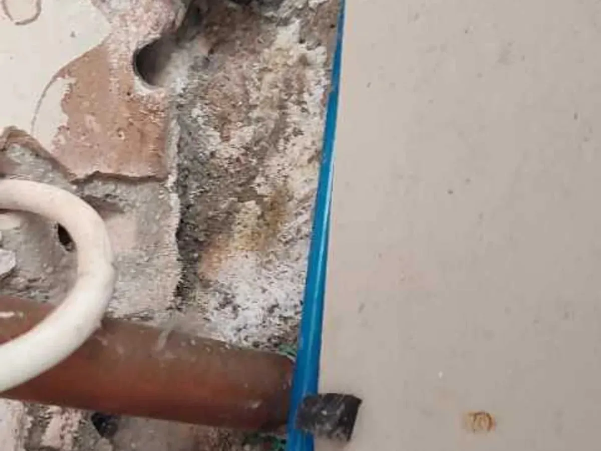 White salt deposits on the screed beside pipes in the manifold cupboard
