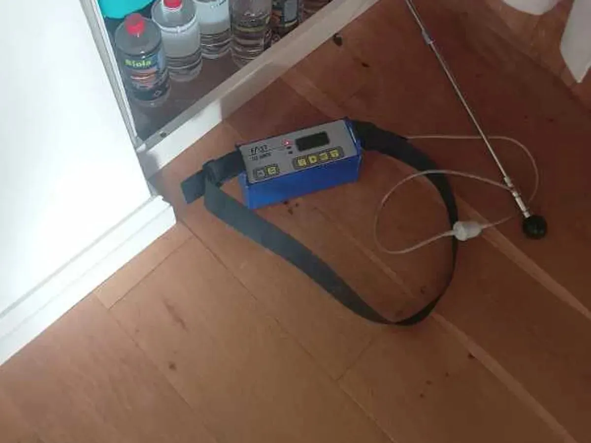Tracer gas detector with a probe lying on a wooden corridor floor