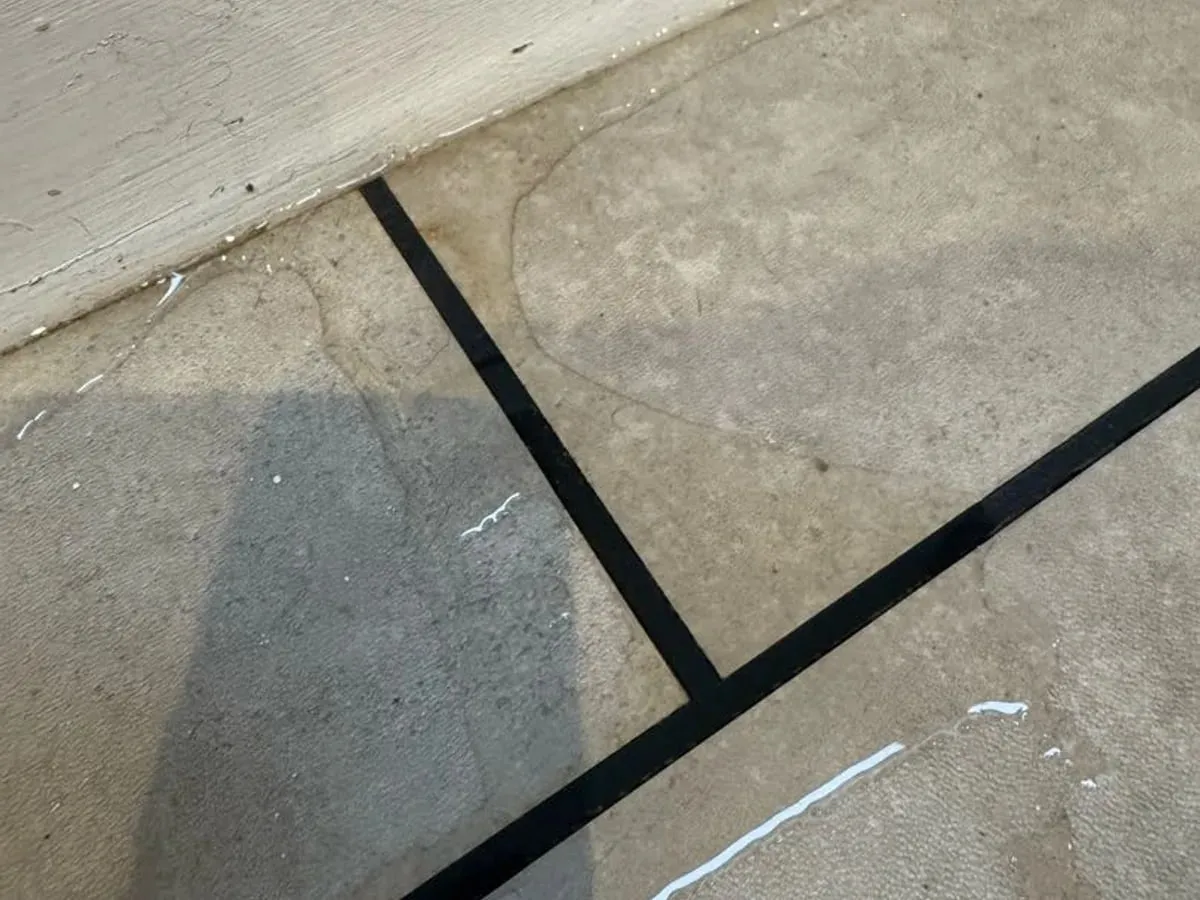 Water pooled on floor tiles against the skirting board